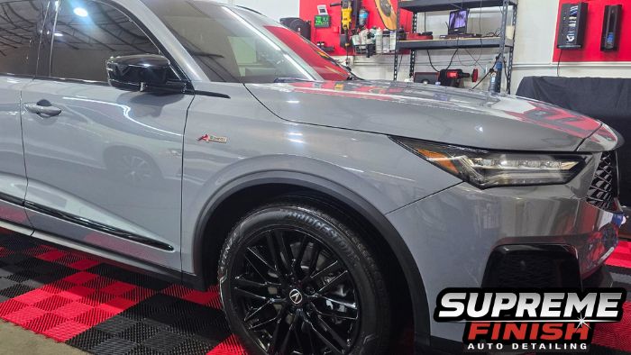Metallic gray Acura MDX A-Spec inside the Supreme Finish detailing shop, showing glossy paint and black wheels