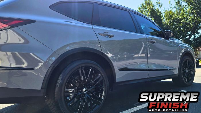 Rear three-quarter view of a gray Acura MDX with reflective body panels and gloss-black wheels